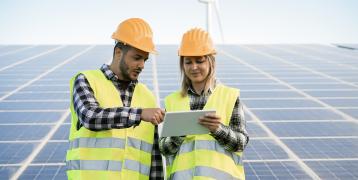 Male and female construction workers in front of solar panels