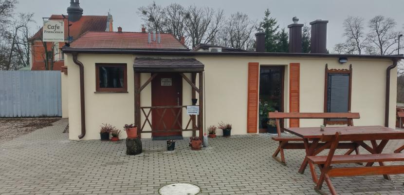 Cafe Francesco The image depicts a small café called "Cafe Francesco," which has been established in former farm buildings belonging to the parish of the Crucified Jesus and Our Lady of Sorrows in Pakość, located on Kalwaria Hill. What makes this café unique is that visitors can enjoy it free of charge. In return for the hospitality, they have the option to leave a donation of any amount as a token of appreciation.