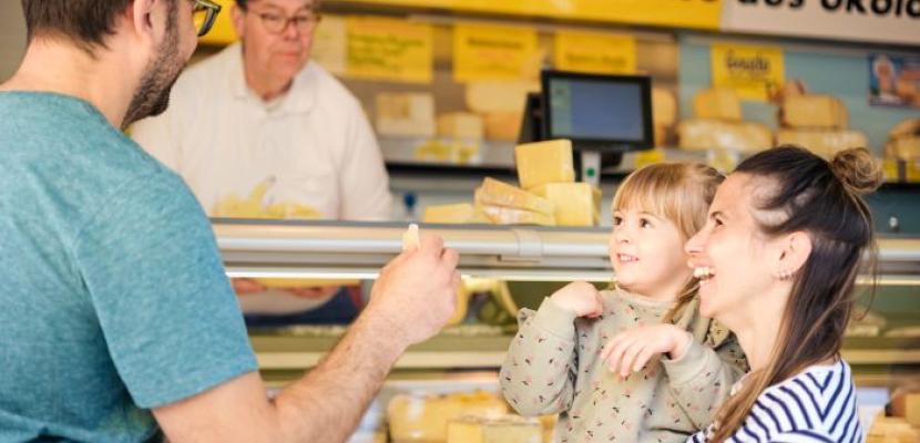 Regional products at a weekly market A family buys regional products from a cheese counter at a weekly market.