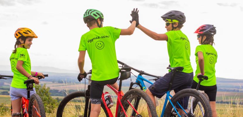 A group of young people sitting on bicycles and high-fiving before sunset Group of young people