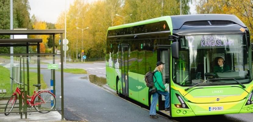 Resource Wisdom Program Jyväskylä Green electric bus stopped on a bus stop and girl getting on the bus.