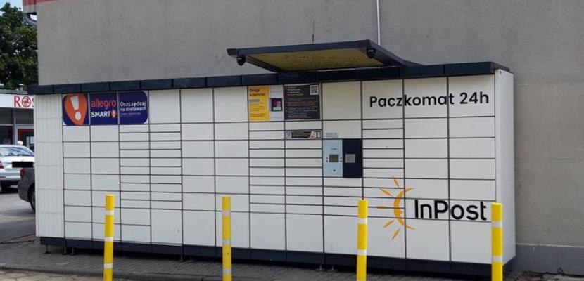 The picture depicts an Automated Parcel Machine situated next to a local supermarket, close to a residential neighborhood.