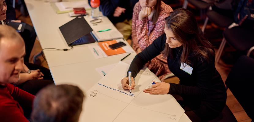 People sitting around table and writing on paper