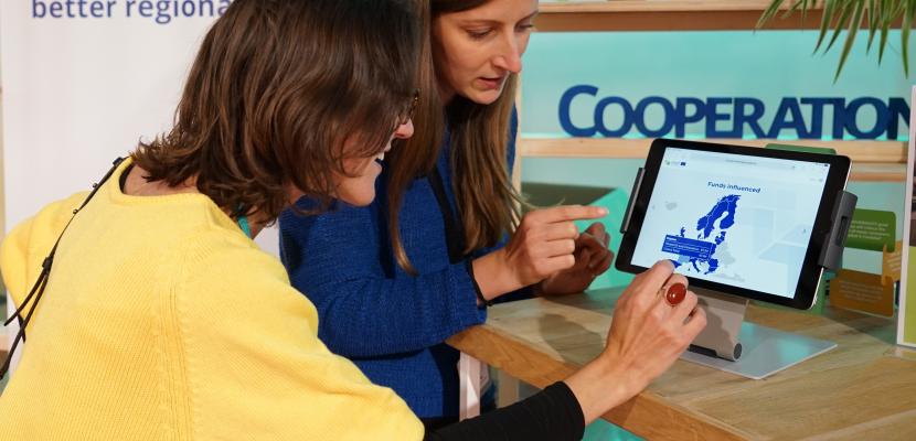 One woman showing to another woman showing a webpage about European funds on a tablet 