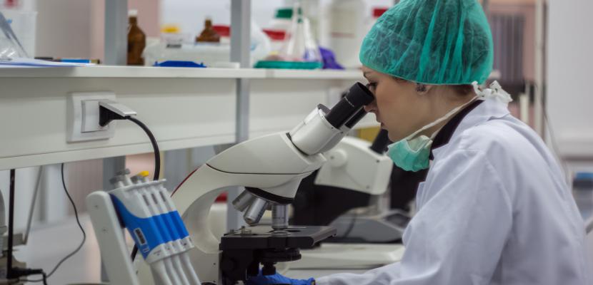 Researcher looking into a microscope