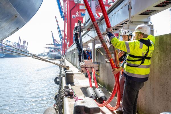 Dock workers handling Shore Side Electricity cables to connect a container vessel to Onshore Power Supply