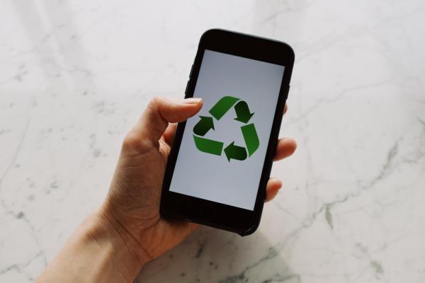 Hand holding phone with green recycling icon 