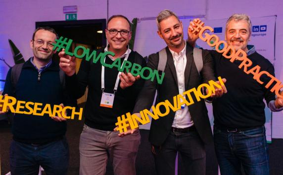 People posing with plastic words saying "lowcarbon #goodpractice #innovation #research"