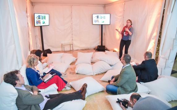 Woman doing a presentation to people sitting in pillows