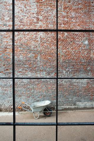Empty wheelbarrow in front of a brick wall