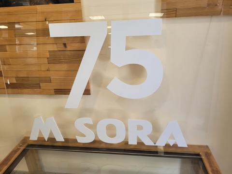 The MSora company logo, as seen during the FBI4EU project visit, symbolizing their commitment to excellence and innovation in the wood industry. A display sign reading "75 M SORA" against a wooden background, showcasing the company's 75th anniversary.