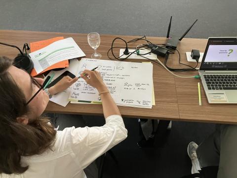 Notes of the meeting were made by drawing. Notes of the meeting were made by drawing: a dark haired girl drawing beside the table.