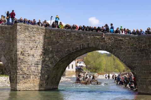 Group of people on a bridge watching a show on the river