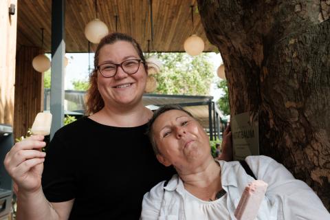 Two women eating ice cream, smiling into the camera.