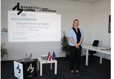 A speaker stands in front of the presentation she will make