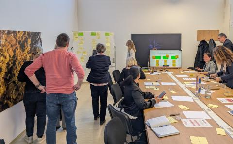Mid-Workshop Momentum: Ideas Unfold at the Whiteboard Participants are gathered in front of a whiteboard, actively engaging in the middle of the workshop.