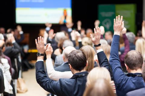 Participants of an event raising hands during a plenary