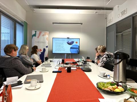 Five stakeholders sitting beside the table and looking to the power point presentation on screen.