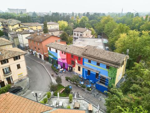 Neighbourhood House in Gattaglio. Top view of the neighbourhood house, consisting of three coloured buildings next to other translational buildings in the neighbourhood.