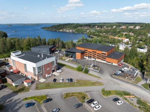 white and brown laboratory building and reddish new laboratory building with Lake Saimaa in the background