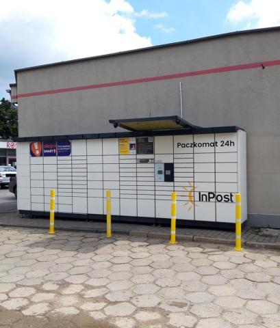 The picture depicts an Automated Parcel Machine situated next to a local supermarket, close to a residential neighborhood.