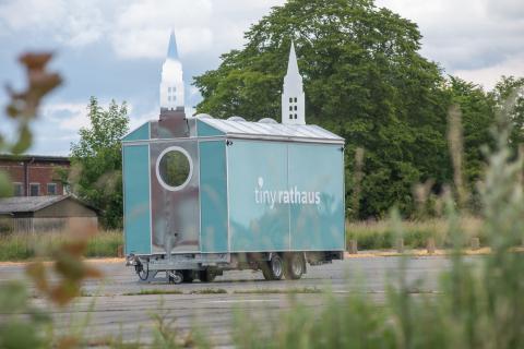 A tiny house on wheels which resembles a tiny townhall.