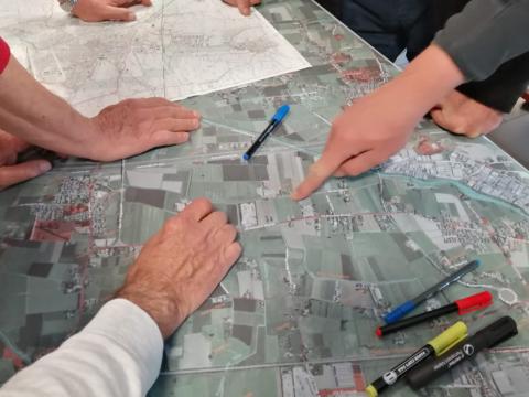 Co-creating trails - Reggio Emilia People (only hands are visible) working on a map of a neighbourhood, with coloured markers