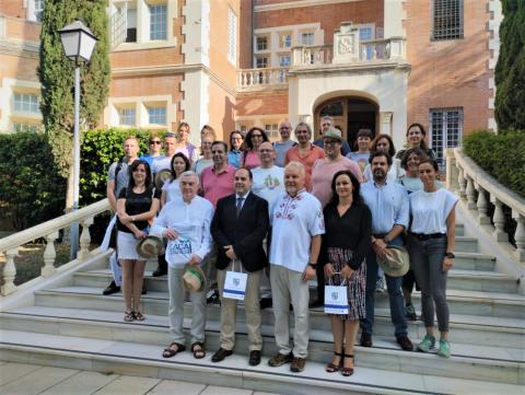 NACAO project partners in Sevilla June 2023. Group of people standing on stairs in front of orange house, in sunshine in Sevilla, Spain.