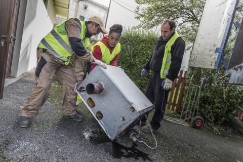 Three people carrying a stove