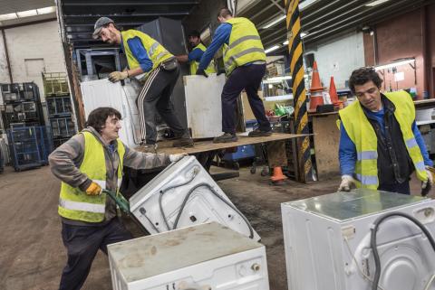 People unloading big electronic and electrical equipments in a centre for reuse and recycling