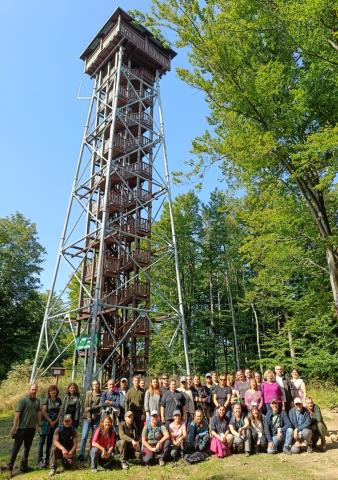 A group photo under an observation tower in a green space