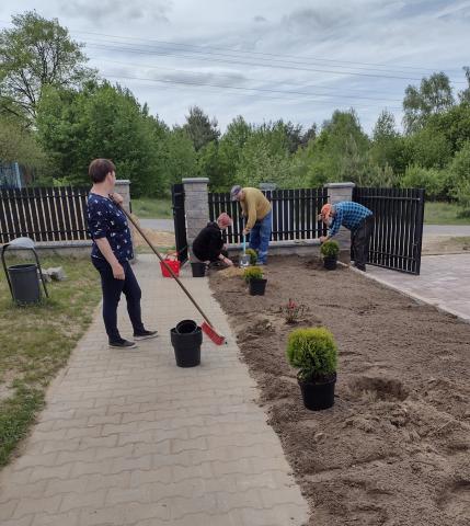 A group of people carry out joint cleaning work on the entrance garden.