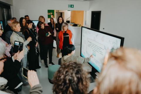 Presentation of learning tools of the Klimapark Group of people looking at the touchscreen