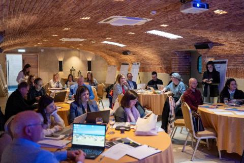 Partners meeting people gathered in a room, looking at presentation