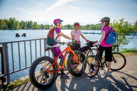 Three cyclists having a break beside lake scenery