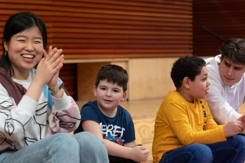 Two adults and two children sitting next to each other, clapping and laughing.