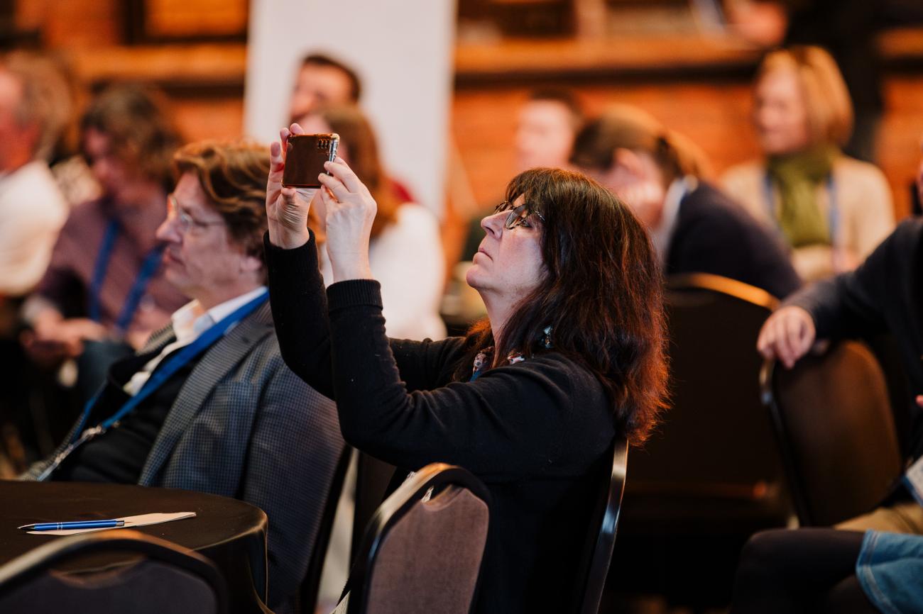 Woman taking picture of the stage at Europe, let's cooperate 2025 in Krakow