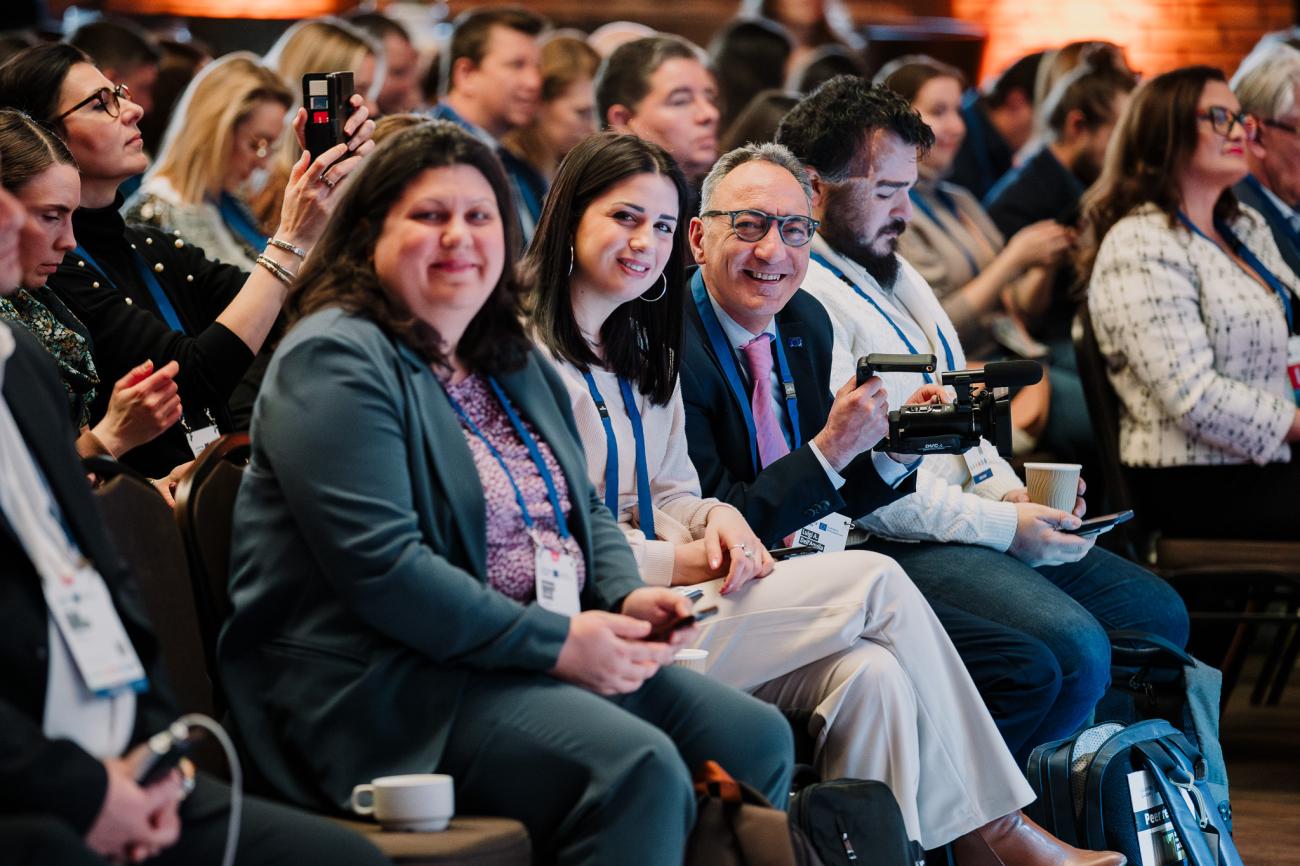Three people smile for the camera at Europe, let's cooperate 2025 in Krakow