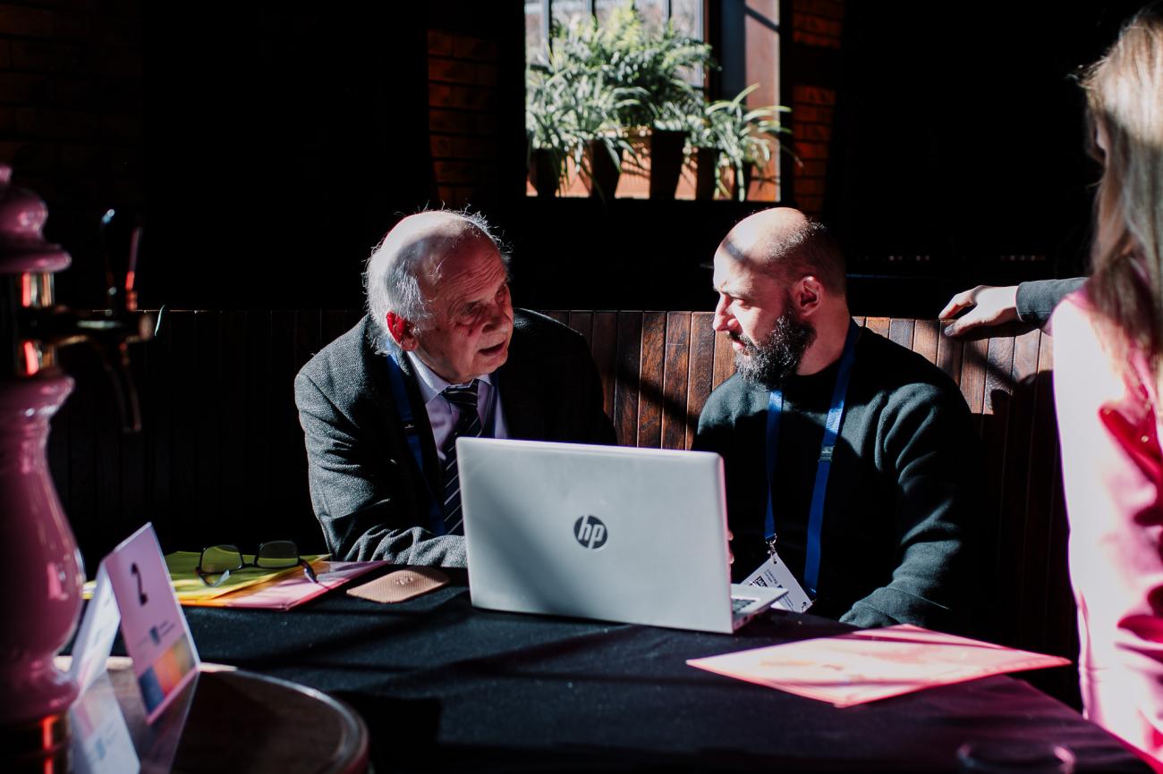 Two men network around a table at Europe, let's cooperate 2025 in Krakow