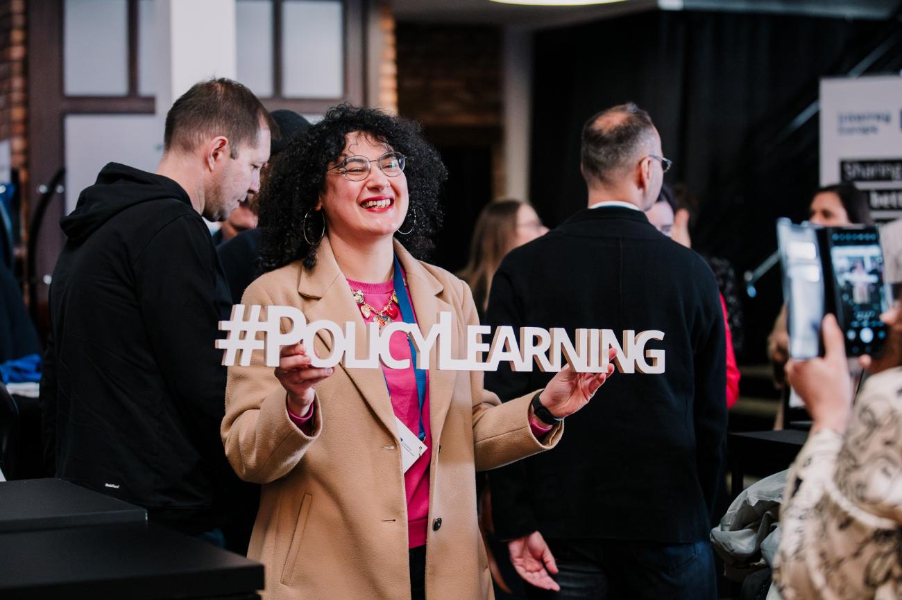 Woman holds up Policy Learning branding at Europe, let's cooperate 2025 in Krakow
