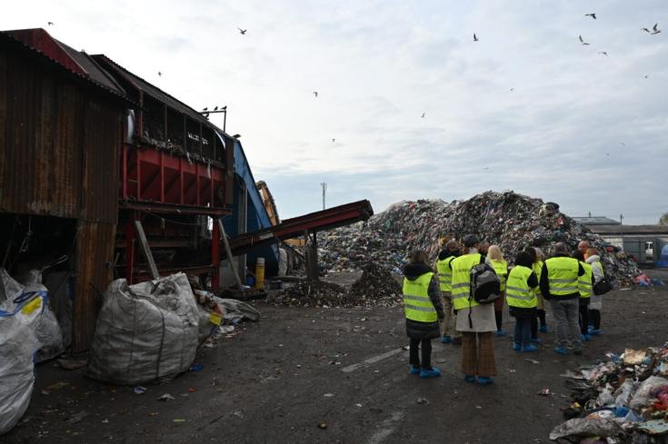 Group of people with yellow vests visiting a waste facilit