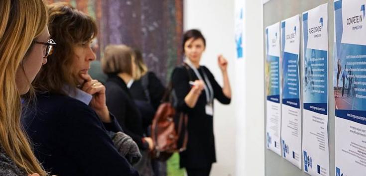 People discussing in front of a wall of informative posters 