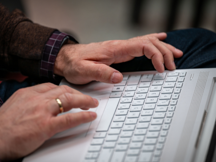 Person uses computer Close up of hands typing on white laptop keyboard.
