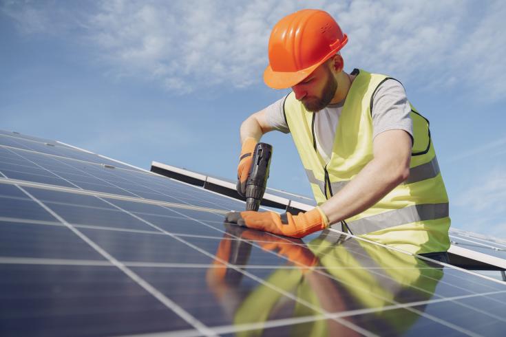 Construction worker installing solar panels on roof
