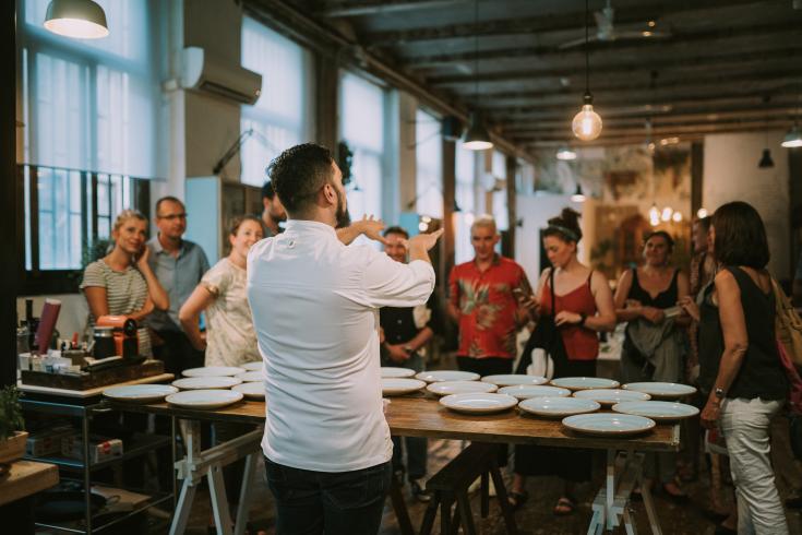 Man in front of table showing products to a group of people