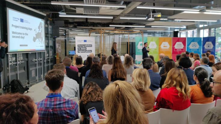A group of people in a meeting room hearing a presentation