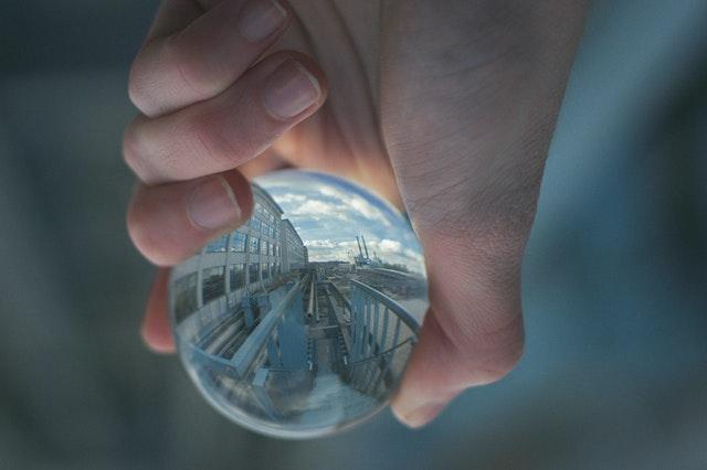 Hand holding a glass ball that reflects building