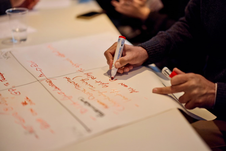 male hand writing on a piece of paper with a red marker male hand writing on a piece of paper with a red marker