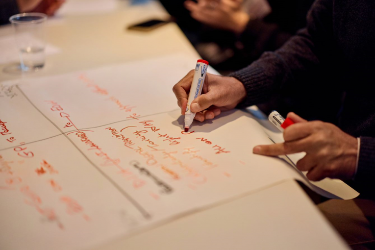 male hand writing on a piece of paper with a red marker