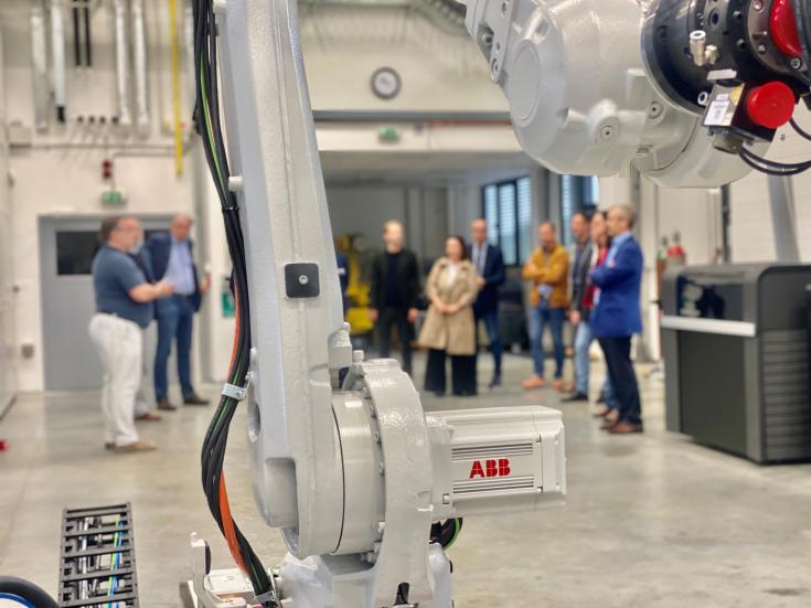 A group of people behind the arm of a robot